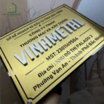 BIỂN TÊN CÔNG TY, Inox 304 Vàng Xước . Tên Cty nổi 1cm Inox Xước Bạc, Đế mica đen 5mm. Ngoài trời. BCT-PMV177